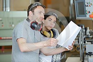 man and woman reading paperwork before using machine