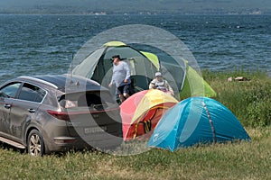 Man and woman relax in a tent camp on the shore of a Large lake in the summer season