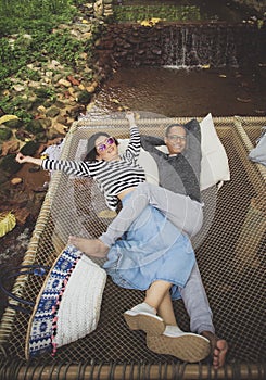 Man and woman relaxing with happiness emotion on net cradle over flowing creek