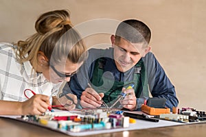 Man and woman repairing computer motherboard in workshop