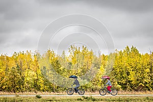 Man and woman riding bicycles along a path surrounded by colourful fall trees.