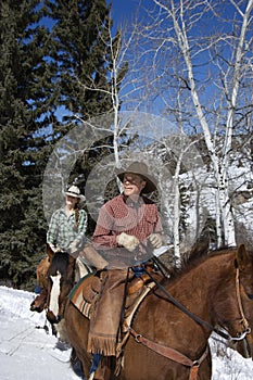 Man and Woman Riding Horses in the Snow