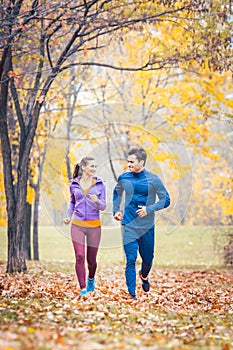 Man and woman running as fitness sport in an autumn park