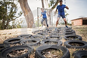 Man and woman running over the tyre during obstacle course