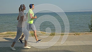 Man and woman running on pavement next to the sea