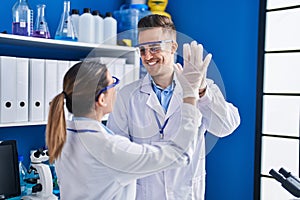 Man and woman scientists high five with hands raised up at laboratory