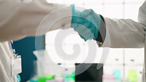 Man and woman scientists speaking and shake hands at laboratory