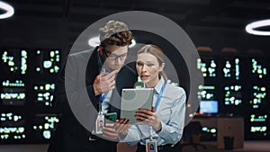 Man woman server technicians working pad computer in night data center closeup