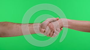 A man and a woman shake hands. Close up of a male and female hand exercising a handshake against a green screen