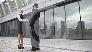 Man and woman shaking hands and smiling, business partners getting acquainted