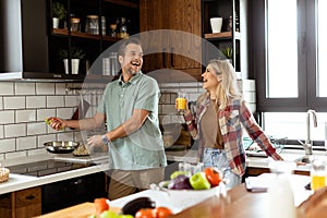 Man and woman sharing a laugh as they cook in a cozy, well-organized kitchen