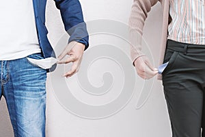 Man and woman showing empty pocket on wall background