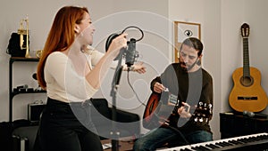Man and woman singing son playing guitar at music studio