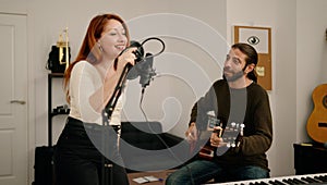 Man and woman singing son playing guitar at music studio