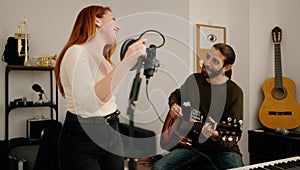 Man and woman singing son playing guitar at music studio