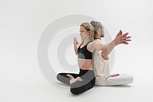 Ð man and a woman sit and meditate on the floor with their backs against each other. Young people practicing tantra yoga