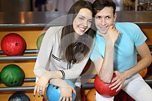 Man and woman sit near shelves in bowling club