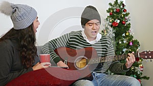 Man and woman sit sofa playing guitar singing song