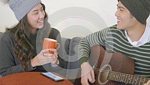 Man and woman sit sofa playing guitar singing song