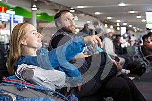 Man and woman sitting at airport terminal and pointing