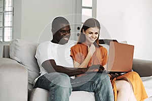 man and woman sitting on the couch in front of laptop communication leisure