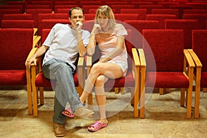 Man and woman sitting in empty presentation hall.