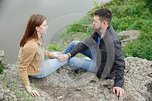 A man and a woman are sitting face to face on a stone platform