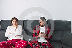 Man and woman sitting on a grey sofa separately after an argument photo