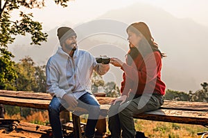 man and woman are sitting on a wooden bench, smiling at each other