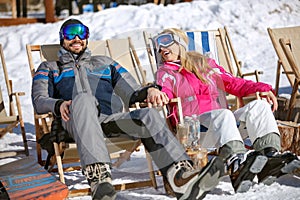 Man and woman skiers sitting in sun lounger