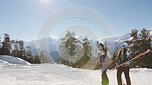 Man and woman with skis in hand to ski resort climb on foot to the top.