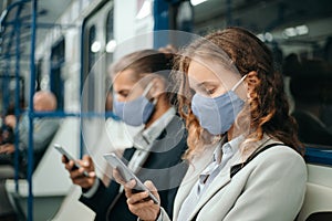 Man and a woman with smartphones sitting in a subway car.