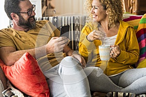 Man and woman smile and enjoy leisure activity at home in morning breakfast time together. People sitting on the sofa in apartment