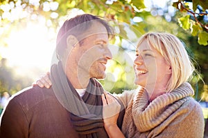 Man, woman and smile in park environment for love anniversary in autumn weather with warm clothes, scarf or date. Happy