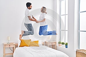 Man and woman smiling confident jumping on bed at bedroom