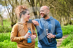 A man and a woman are smiling and holding water bottles.