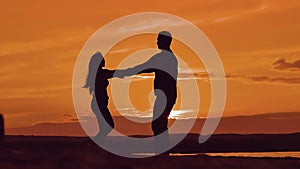 Man and woman spinning hold hands. silhouette man and girl of a happy young married couple slow dancing outside at