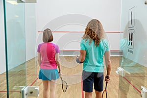 Man and woman squash player holding racket view from back