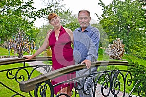 The man and the woman stand on the decorative bridge in the park