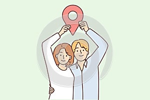 Man and woman stand in embrace and show large geotag to share coordinates for house party