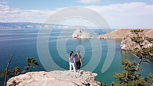 A man and a woman are standing on a cliff above the sea. Lake Baikal. Aerial shooting from the drone.