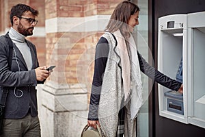 Man and woman standing in front of cash machine