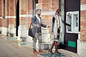 Man and woman standing in front of cash machine