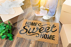 Man and Woman Standing By Home Sweet Home Welcome Mat, Moving Boxes