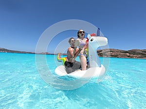 a man and woman standing on an inflatable swan floaty in Lucky Bay, Esperance