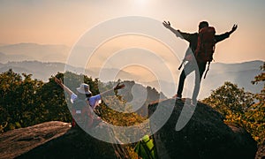 man and woman are standing on a mountain top, both wearing backpacks