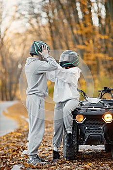 Man and woman standing near a quad bike in autumn forest