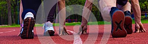 A man and a woman are standing on a running track at a stadium in summer. Rear view, close-up. People are ready to start