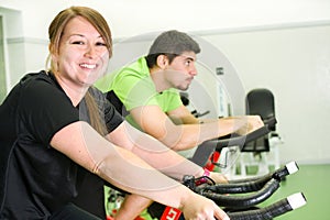 Man and woman with stationary bicycle in gym