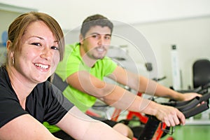 Man and woman with stationary bicycle in gym